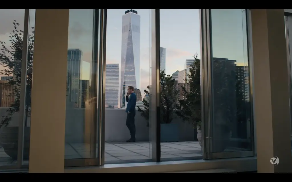 A woman is standing in front of a window looking at the skyline.