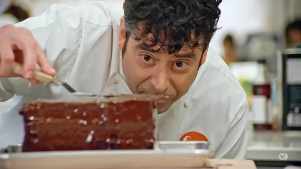 A chef is preparing a chocolate cake in a kitchen.