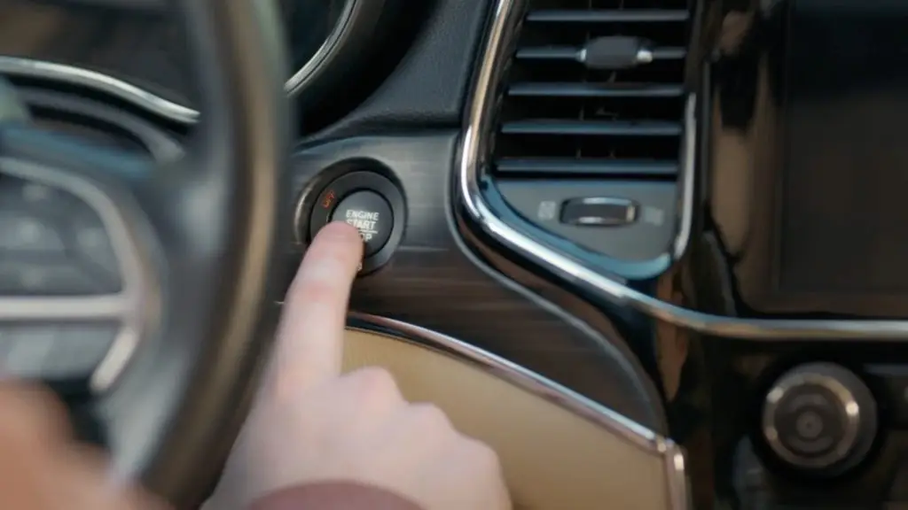 A person is pressing a button on the steering wheel of a car.