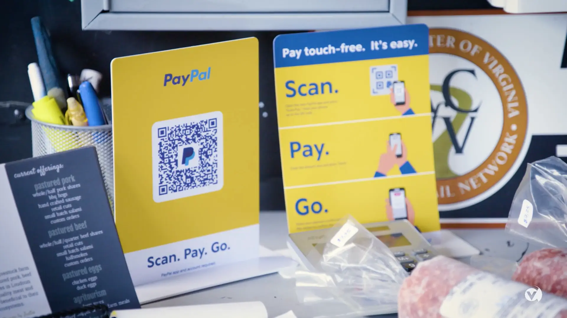 A desk with a PayPal qr code sign for online payments and other items.