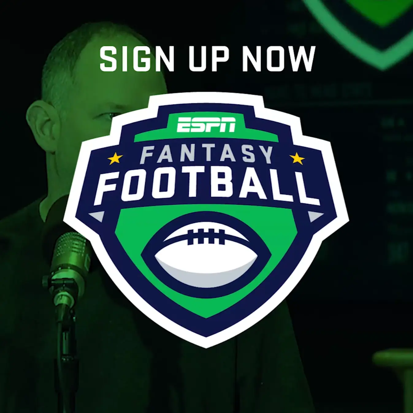A man in front of a microphone with the words sign up for fantasy football on social media.