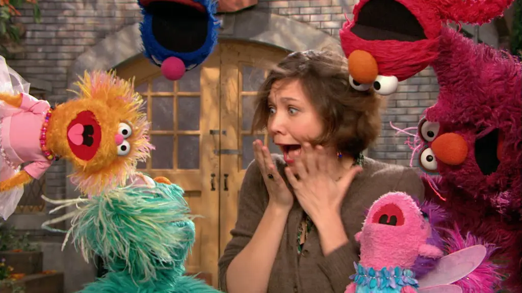 A woman is surrounded by a group of Sesame Street puppets, providing entertainment for all.