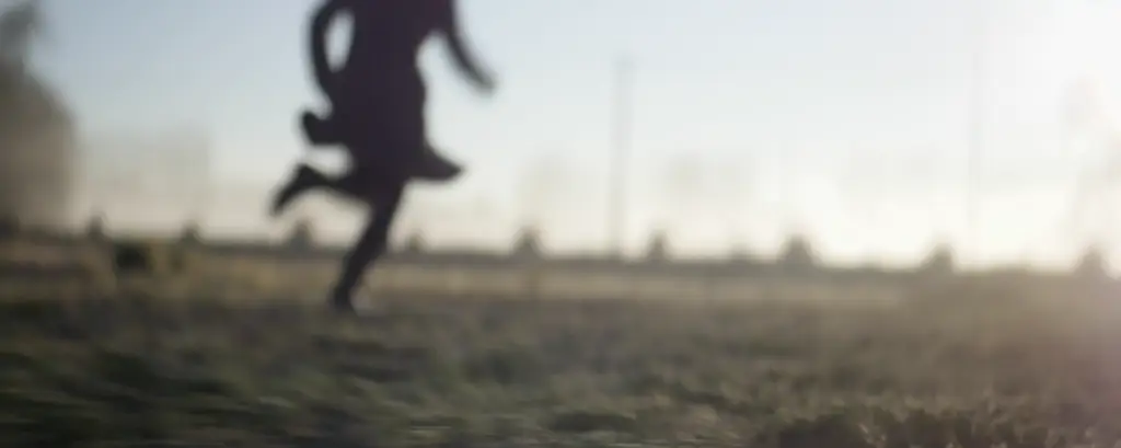 A blurry image of a woman running in the field for entertainment.