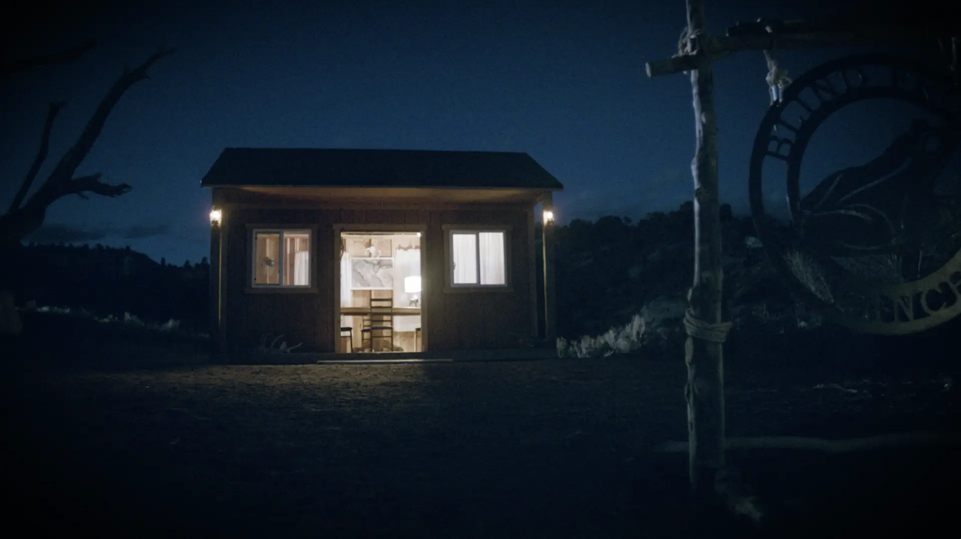A small cabin in the woods at night, featuring entertainment.