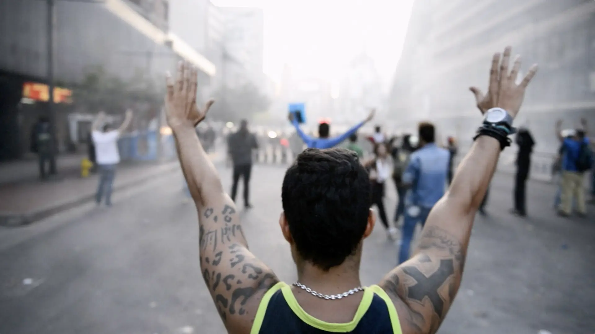 A man raises his arms in the middle of a street featuring entertainment.