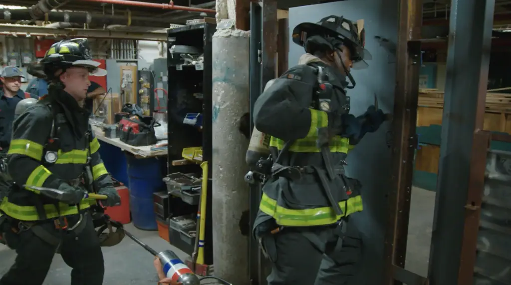 Two firemen working on a door in a factory ignites interest.
