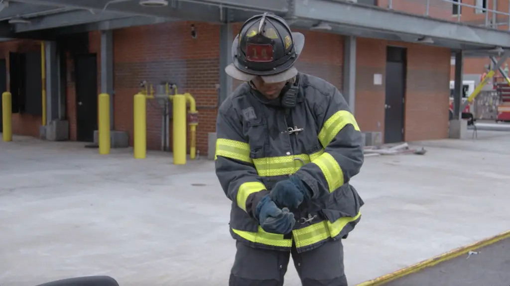 A firefighter putting on a helmet ignites.