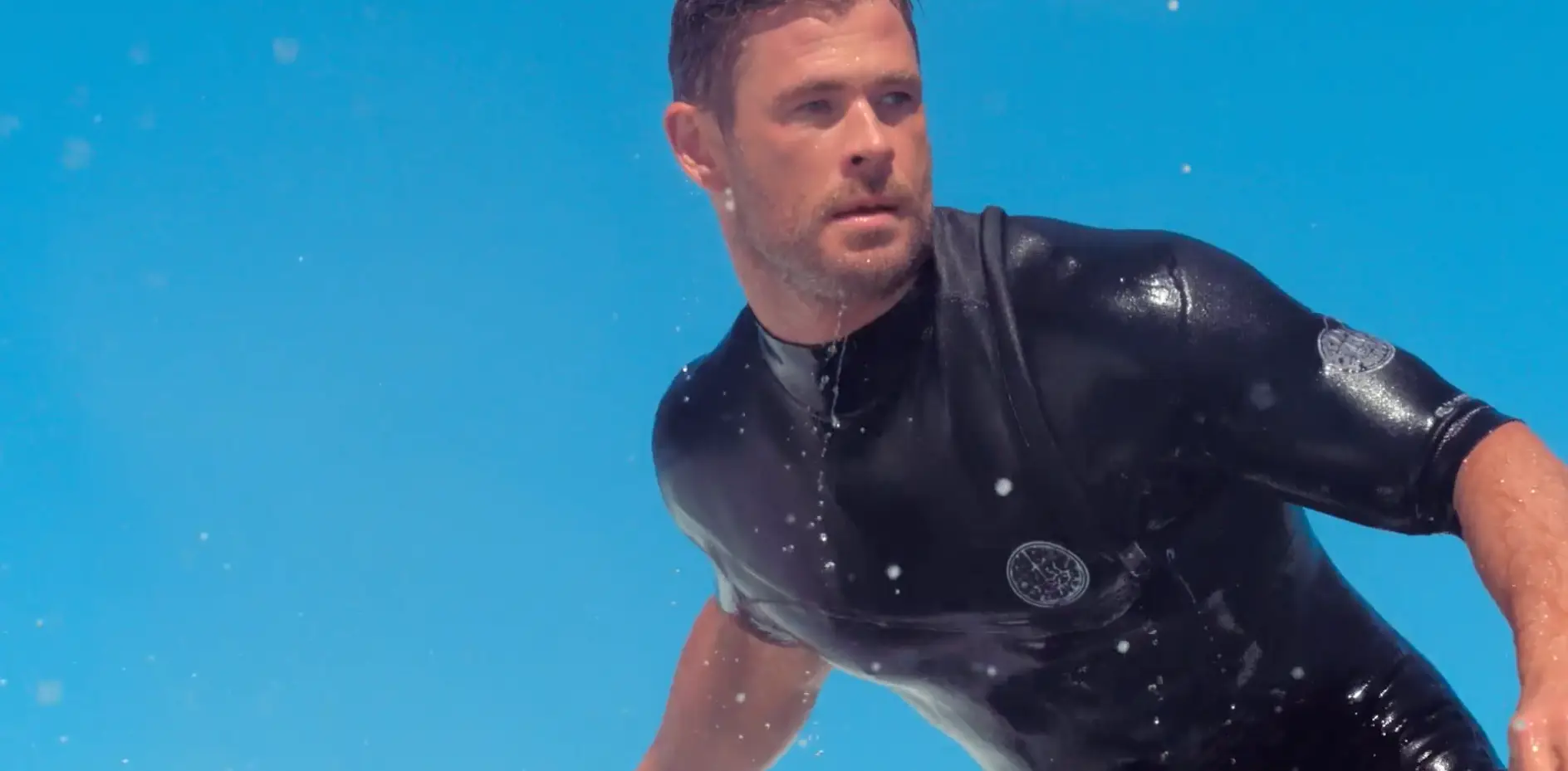 A man in a wetsuit riding a surfboard, providing entertainment.