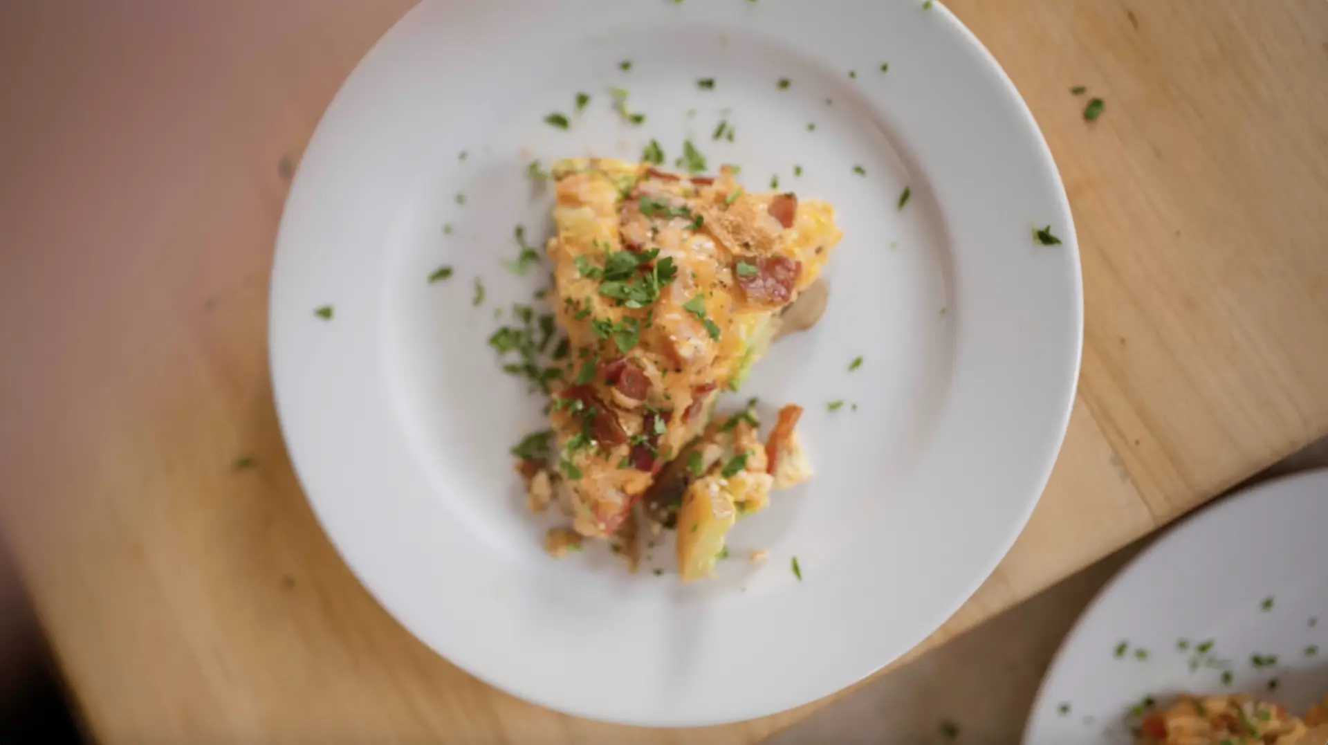 A piece of bacon and egg quiche on a plate.