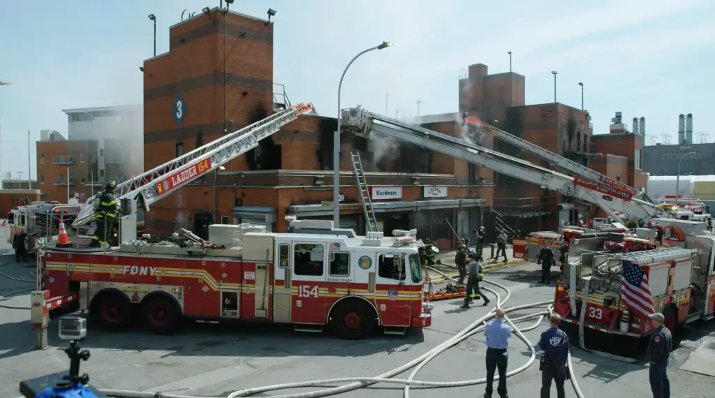 A fire scene ignites with several fire trucks in front of a building.