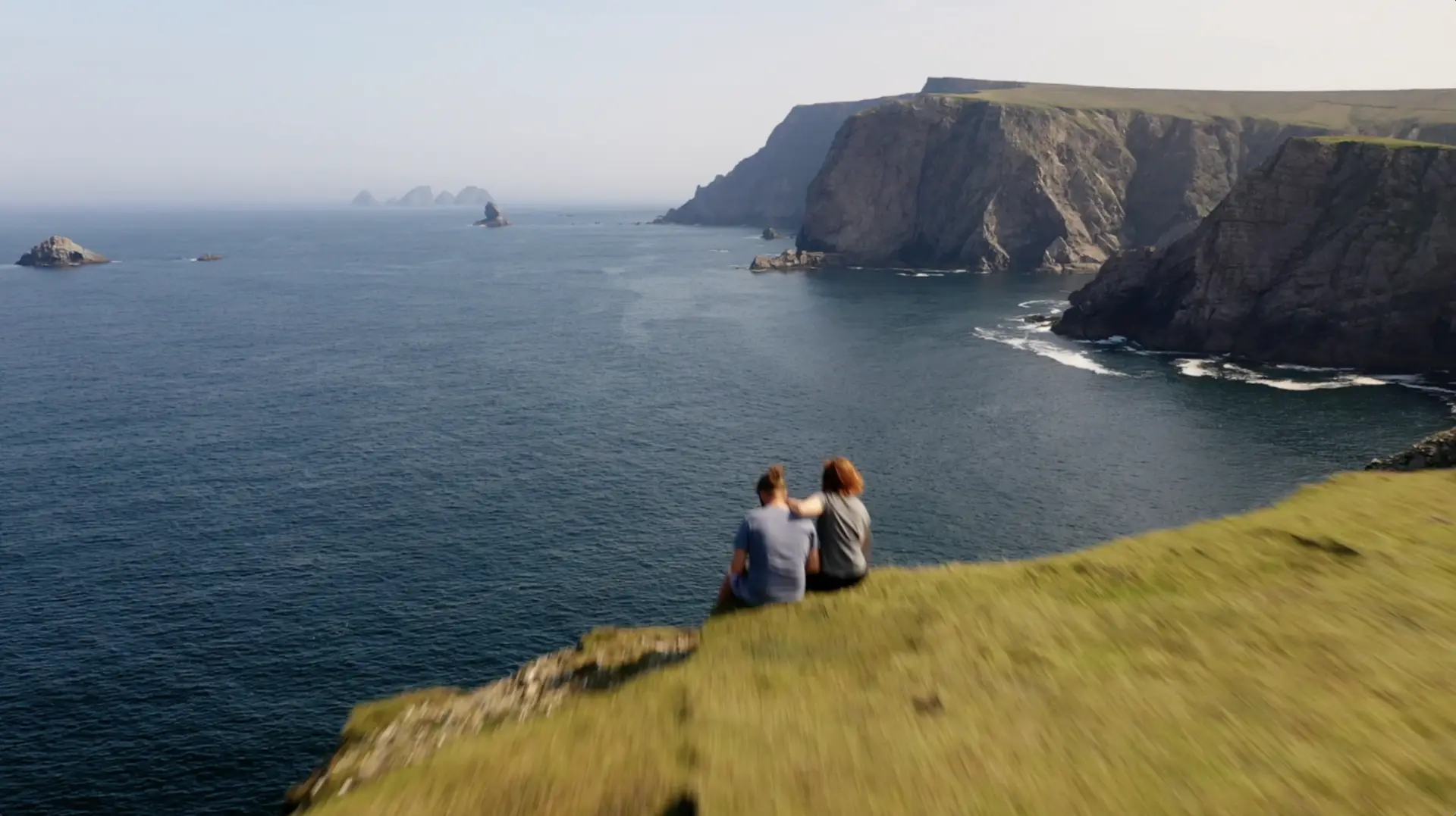 Two people sitting on a cliff overlooking the ocean, captured by Trip Canvas.