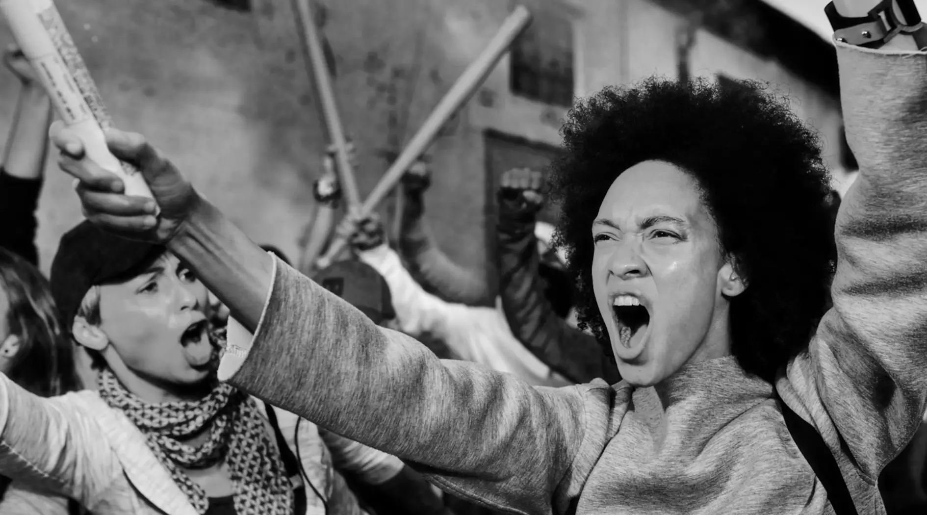 A black and white photo of a woman shouting in a crowd, capturing a moment emblematic of Press Freedom Defense Fund's mission.