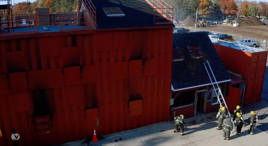 A firefighter is standing next to a red building, inspiring content for LIVE 2023.