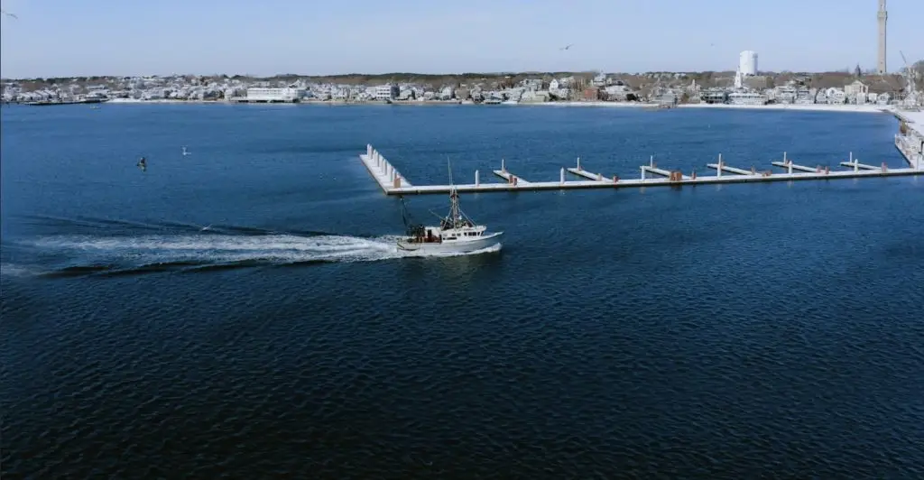 An aerial view of a branded work boat in the water near a dock.