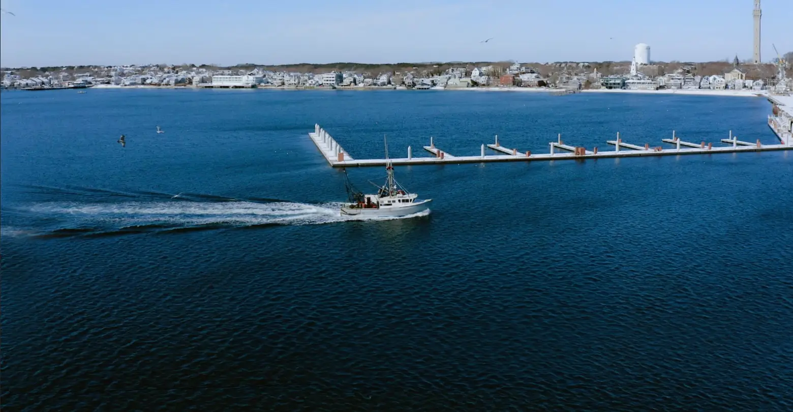 An aerial view of a branded work boat in the water near a dock.