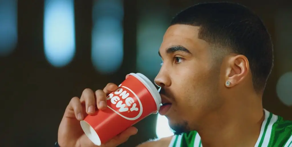 A basketball player drinking a cup of coffee, featured in an advertising campaign by a leading digital marketing media company.