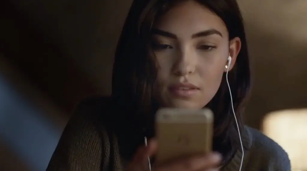 A woman wearing Rockbot earphones looking at her phone.