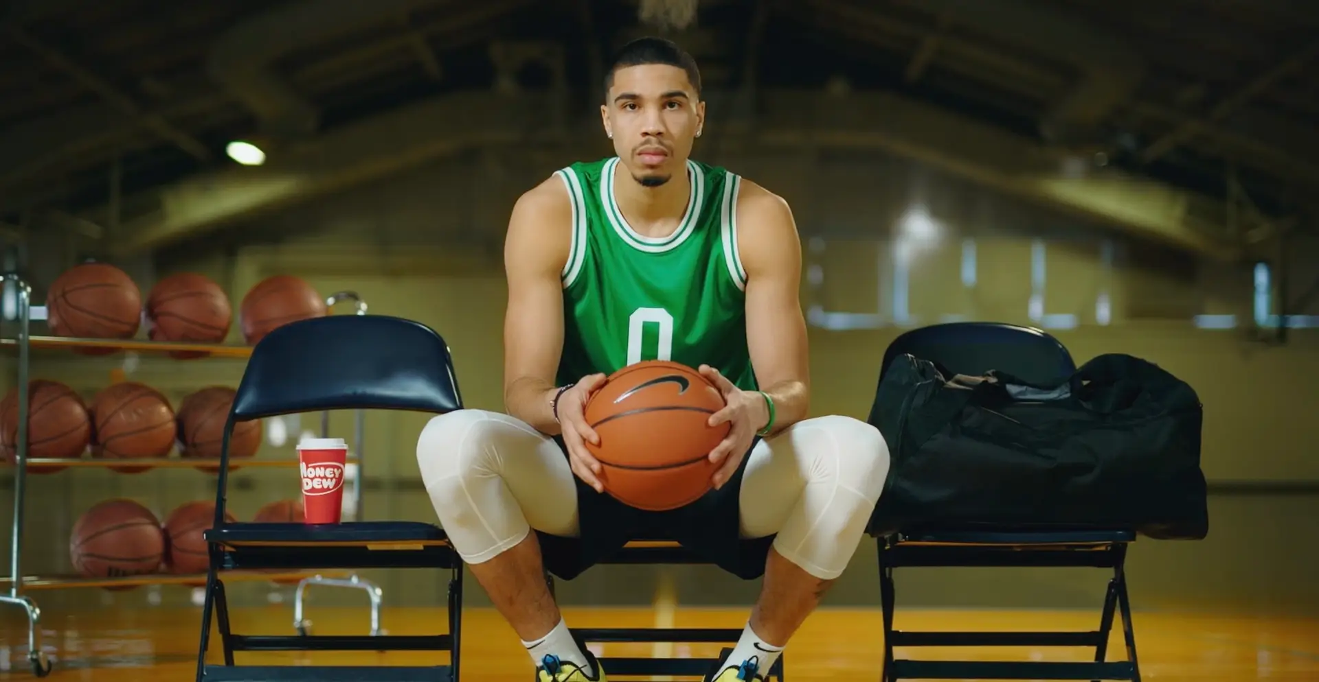 A basketball player sitting on a live 2023 home page chair holding a ball.