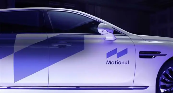 A white car with a blue logo on the side, LIVE 2023.