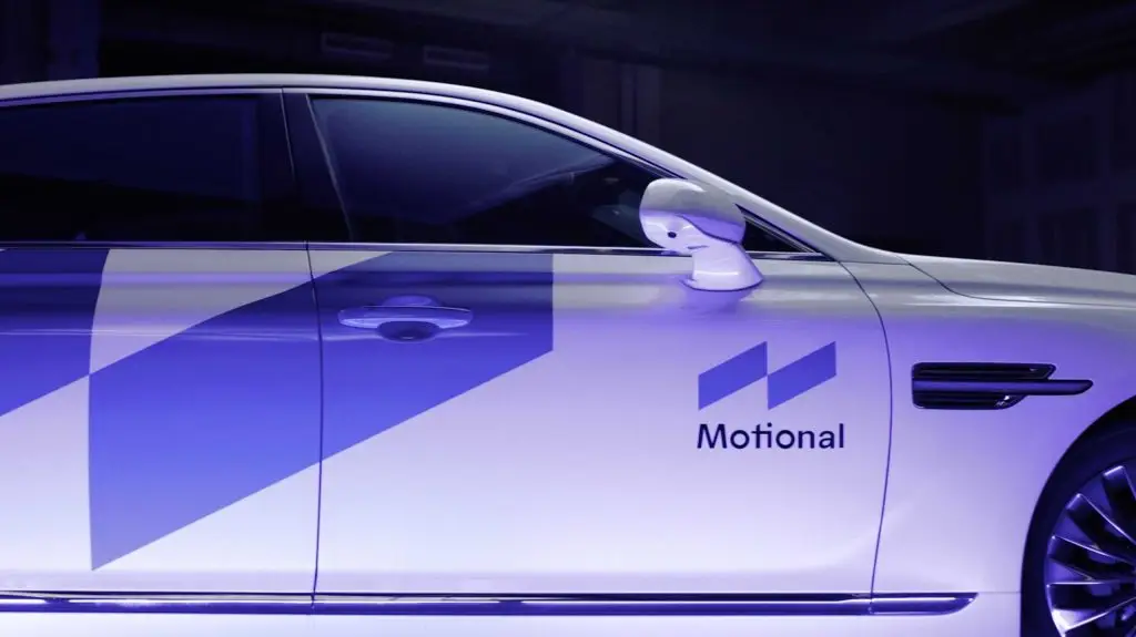 A white car with a blue and white Motional logo on it, ready for its product reveal.