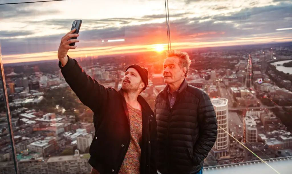 Two men are taking a selfie on the top of a building in Boston.