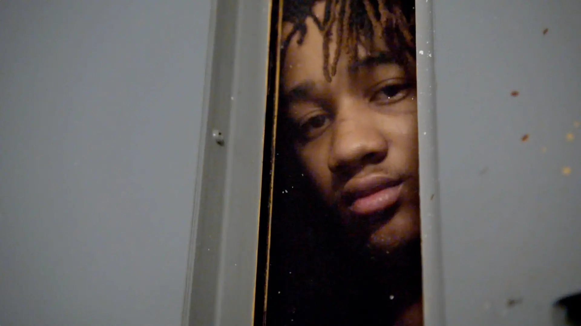 A man with dreadlocks, featuring in "60 Days In," peeking out of a door.