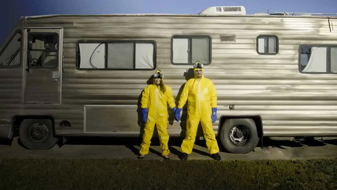 Two individuals in yellow hazmat suits standing beside an RV, featured in our Sales Content Library.
